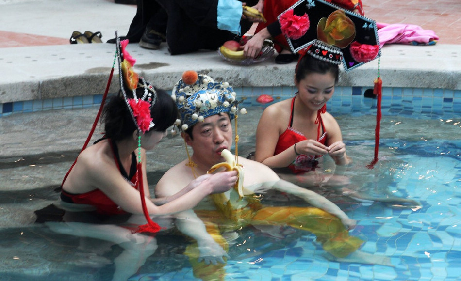 At a time when officials have been told to rein in lavish spending and banquets, one man has taken decadent pampering to a whole new level by splashing out 100, 000 yuan ($16,045) to be bathed like an emperor. The Shanxi man, whose identity will probably not remain unknown for long, bid the obscene amount of money to be the first guest at a new bathing center in Shangtang township, Henan province, on Feb 2, 2013. Faux concubines and eunuchs clustered around him, giggling and feeding him bananas as onlookers and media snapped images of the event in a province littered with poverty. It was reported at the beginning of the month that a number of migrant workers blocked the entrance to the new bathing center claiming they were owed unpaid salary for construction. The move and event attracted widespread criticism online. [Photo by Wang Zhongju/ Image China]