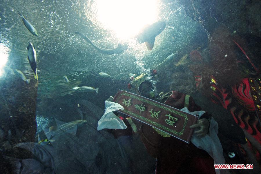 A diver dressed as the Chinese "God of Fortune" gives blessings to tourists at the Underwater World in Singapore, Feb. 5, 2013. The Chinese lunar New Year is to be celebrated on Feb. 10 this year. (Xinhua/Then Chih Wey) 