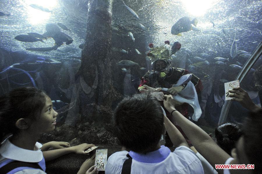 Students interact with the Chinese "God of Fortune" to receive blessings at the Underwater World in Singapore, Feb. 5, 2013. The Chinese lunar New Year is to be celebrated on Feb. 10 this year. (Xinhua/Then Chih Wey) 