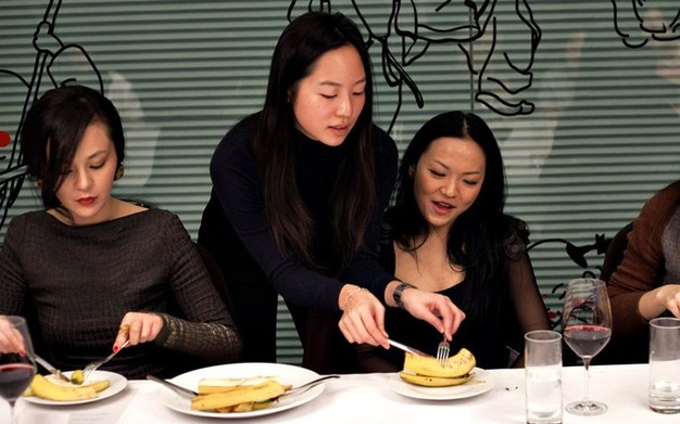 Ladies learn how to use fork and knife to cut banana. (Photo/Xinhua)