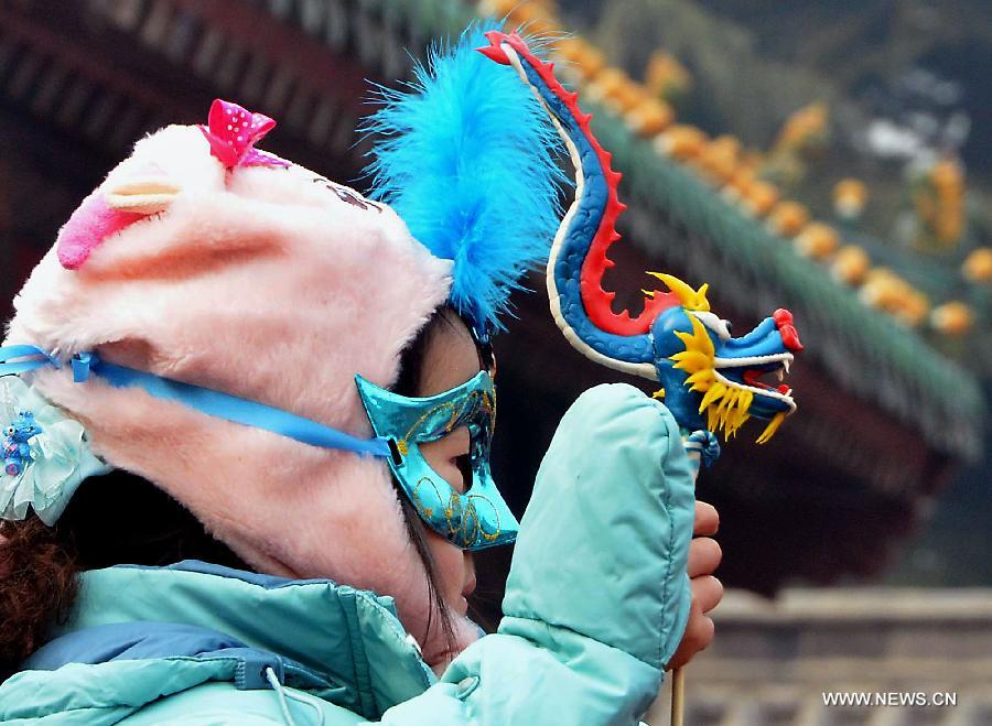 File photo taken on Jan. 23, 2012 shows a girl holding a dough figurine of dragon at a temple fair in Zhengzhou, capital of central China's Henan Province. 2012 was the Year of the Dragon in the Chinese Zodiac. Chinese Zodiac is represented by 12 animals to record the years and reflect people's attributes, including the rat, ox, tiger, rabbit, dragon, snake, horse, sheep, monkey, rooster, dog and pig.(Xinhua/Wang Song) 