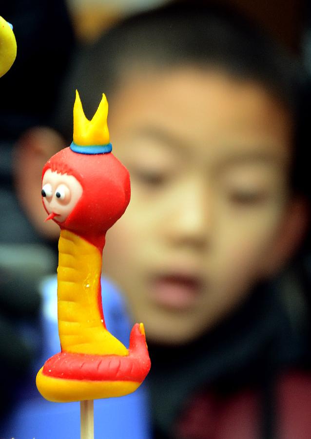 A boy selects "snake" dough figurines at a temple fair in Zhengzhou, capital of central China's Henan Province, Feb. 10, 2013. Chinese people ushered in the Year of the Snake on Feb. 10 and various snake handicrafts can be seen at temple fairs, a Chinese cultural gathering usually held around the time of the Chinese New Year. (Xinhua/Wang Song)