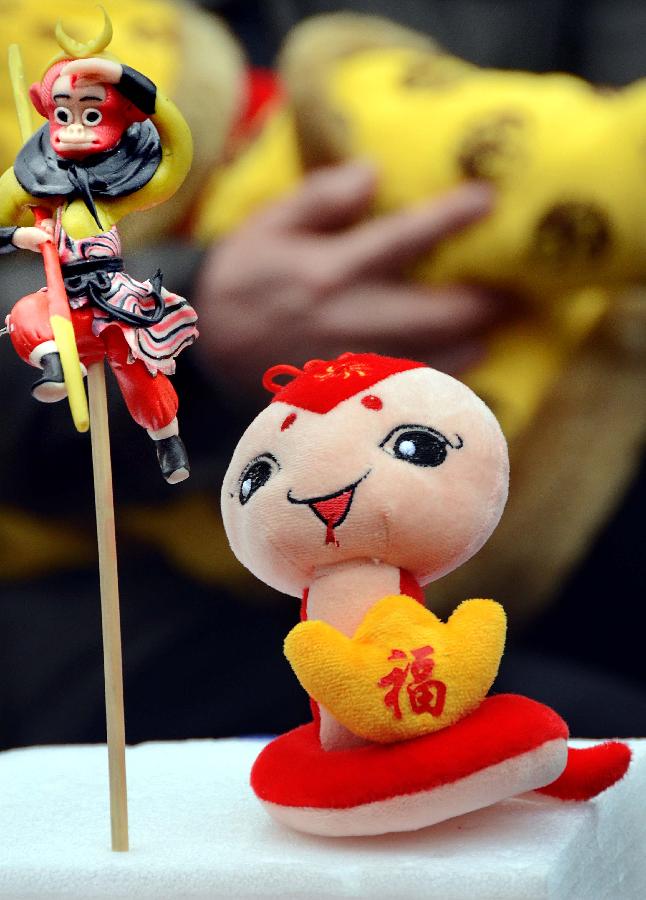 A cute "snake" plush toy is laid beside dough figurine "Monkey King" at a temple fair in Zhengzhou, capital of central China's Henan Province, Feb. 10, 2013. Chinese people ushered in the Year of the Snake on Feb. 10 and various snake handicrafts can be seen at temple fairs, a Chinese cultural gathering usually held around the time of the Chinese New Year. (Xinhua/Wang Song)