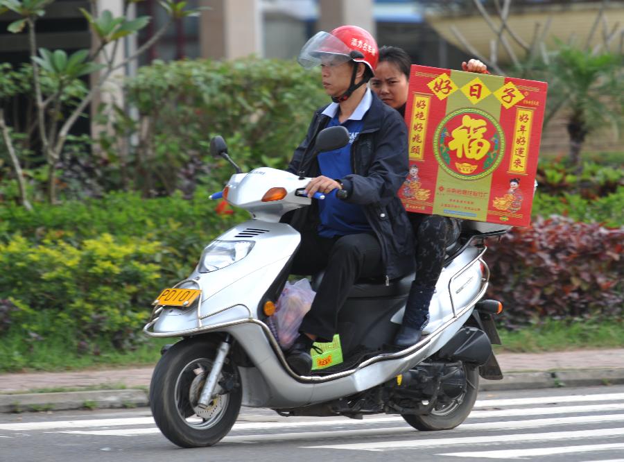A couple ride a motorcycle to the wife's family in Qionghai City, south China's Hainan Province, Feb. 11, 2013. It is the second day of this year's Lunar New Year, or Spring Festival, on Feb. 11, when Chinese married women usually follow a tradition to visit parents with their husbands. (Xinhua/Meng Zhongde) 