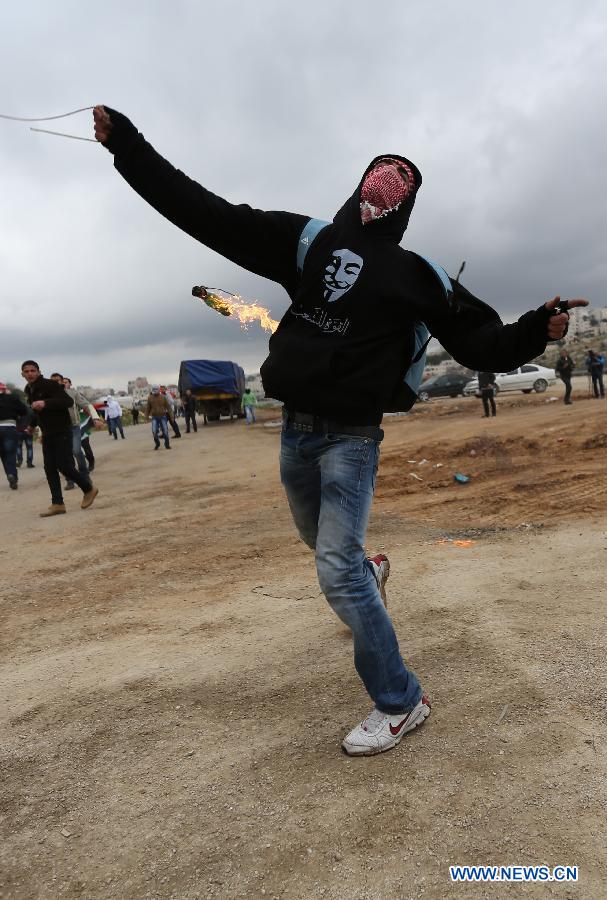 A Palestinian protestor throws stones towards Israeli troops outside Ofer Prison near the West Bank city of Ramallah on Feb.12, 2013. Five protestors supporting Palestinian prisoners were reported injured during the clashes. (Xinhua/Fadi Arouri)