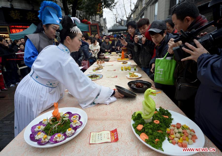 Hosts in ancient costumes introduce dishes to visitors at a banquet in Hangzhou, capital of east China's Zhejiang Province, Feb. 12, 2013. To celebrate the Spring Festival, or the Chinese Lunar New Year, some restaurants in Hangzhou offered free dishes to visitors for taste. (Xinhua/Shi Jianxue)