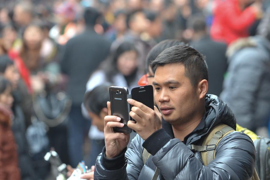 A man takes photos with his cellphone on a street of the Ciqikou Town in southwest China's Chongqing Municipality, Feb. 13, 2013. Large amount of tourists visited the time-honored Ciqikou during the Spring Festival holiday. (Xinhua/Liu Chan) 