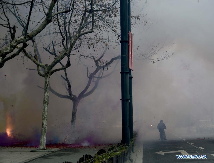 A local citizen rides through dense smoke caused by firecrackers on Fengqi Road in Hangzhou, capital of east China's Zhejiang Province, Feb. 16, 2013. Saturday marks the first working day after the one-week Spring Festival break which started on Feb. 9. Setting off firecrackers on this day is a traditional custom for businessmen to pray for a booming year. (Xinhua/Shi Jianxue)