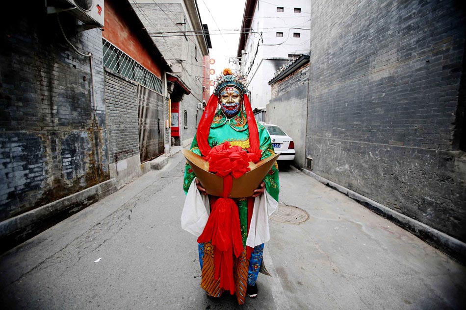 A man in the costume of the "god of wealth" stands in the hutong near the Changdian temple fair in Beijing, Feb. 14, 2013. Chinese has the custom of greeting the "god of wealth" with hope of bringing good fortune for the whole year on the fifth day of the Lunar New Year, which fell on Feb. 14 this year. (Xinhua/Li Fangyu)