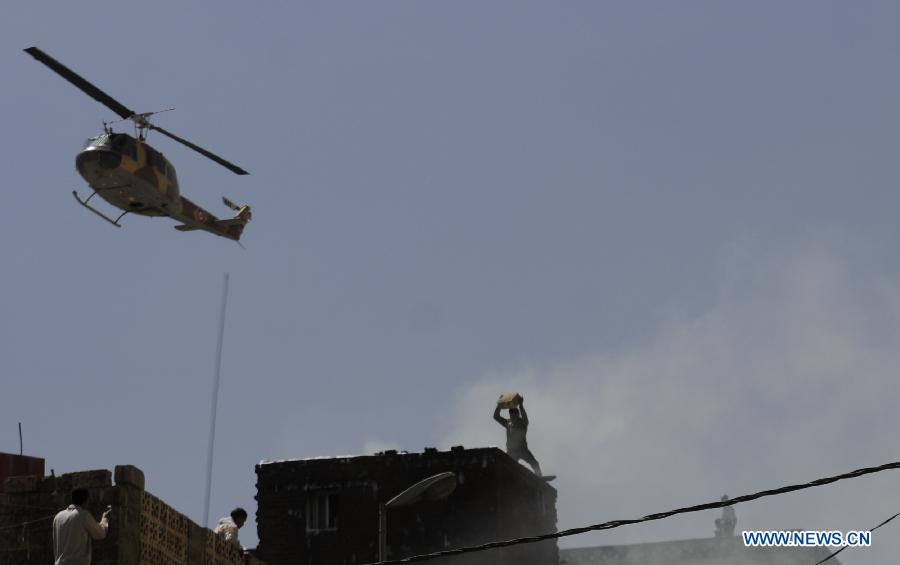 A rescue helicopter hovers above the crash site in Sanaa, Yemen, Feb. 19, 2013. A Yemeni military helicopter on a training mission crashed in a crowded neighborhood in central capital Sanaa on Tuesday, leaving at least nine people dead and 23 others injured, local officials and witnesses said. (Xinhua/Mohammed Mohammed)  