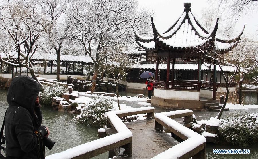 Tourists take photos at the Humble Administrator's Garden in Suzhou, east China's Jiangsu Province, Feb. 19, 2013. Many cities in eastern and central China were hit by a snowfall on Feb. 19. (Xinhua/Zhu Guigen) 