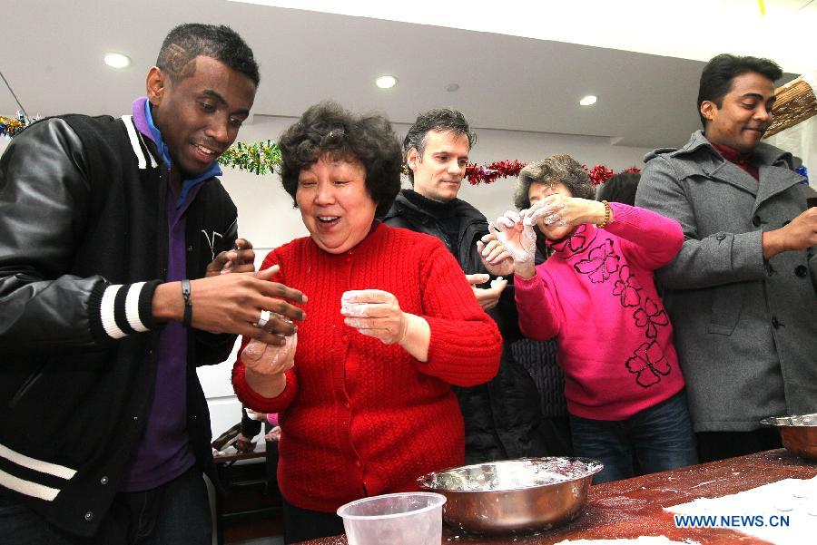Ma Liang (1st L) from Madagascar learns to make the Yuanxiao, glutinous rice flour dumpling with sweetened stuffing, at a community in Shanghai, east China, Feb. 21, 2013. Some foreign students on Thursday came to a community in Shanghai to feel the atmosphere of the upcoming Lantern Festival. (Xinhua/Chen Fei) 