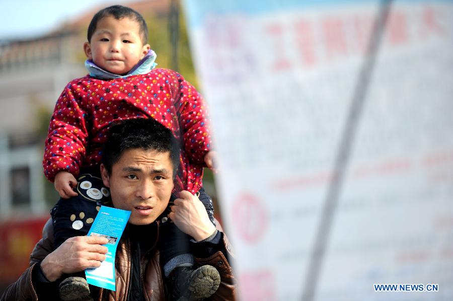 A man looks at the employment information with his kid at a job fair in Changfeng of east China's Anhui Province, Feb. 22, 2013. More than 36 companies participated in the job fair here on Friday with over 3,000 employment positions. (Xinhua/Liu Junxi) 