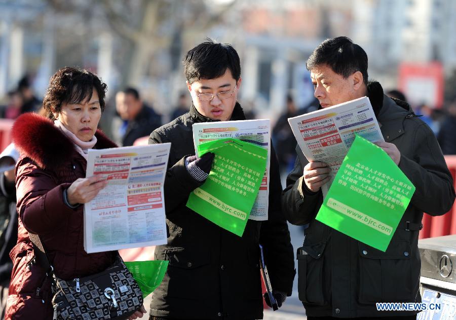  A college graduate (C) and his parents read employment information at a job fair in Beijing, capital of China, Feb. 23, 2013. About 25,000 job opportunities were offered at the job fair. (Xinhua/Luo Xiaoguang) 
