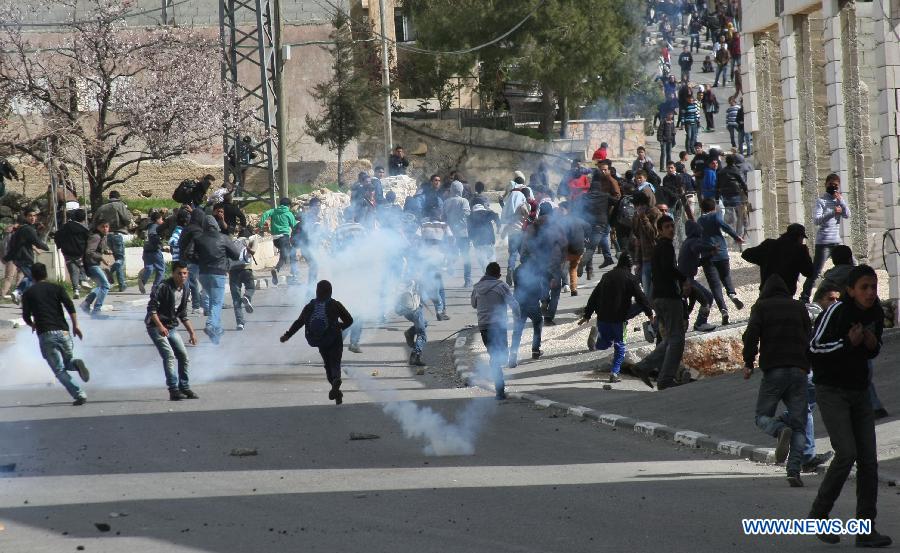 Palestinian protestors try to take cover from tear gas fired by Israeli soldiers during clashes erupted in protest against the death of the Palestinian prisoner Arafat Jaradat in Asir town near the West Bank city of Hebron on Feb. 24, 2013. Thousands of Palestinian prisoners in Israeli jails rejected meals on Sunday to protest against an inmate's death a day earlier, local media reported. (Xinhua/Mamoun Wazwaz)