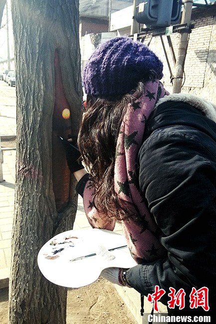 Student painter Wang Yue shows her talent by painting tree holes in Shijiazhuang, capital city of Hebei Province. (Photo/CNS)