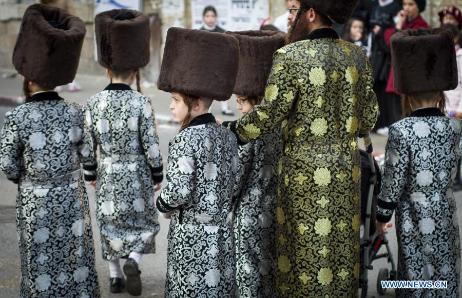 An Ultra-Othordox Jewish family dressed in disguises walk in a street during Purim festival, a Jewish colorful and popular holiday, in Jerusalem, on Feb. 25, 2013. In Jerusalem, Purim was celebrated from sunset on Sunday, Feb. 24, until sunset on Monday, Feb. 25, one day later than it is in the rest of the world. (Xinhua/Yin Dongxun) 