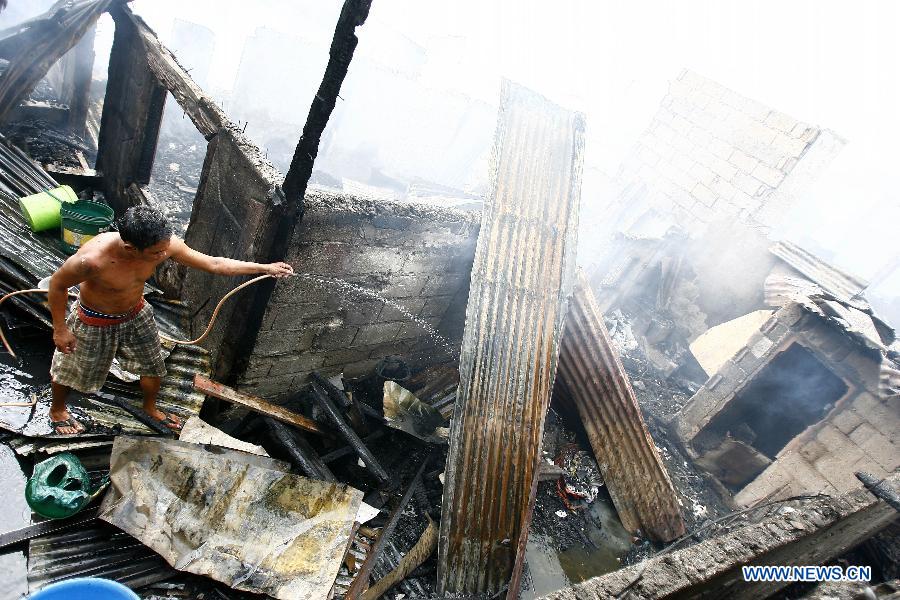 A resident douses the burnt house with water after a fire hit a residential area in Valenzuela City, the Philippines, Feb. 27, 2013. More than 400 shanty houses were destroyed by the fire, leaving 500 families homeless. (Xinhua/Rouelle Umali) 