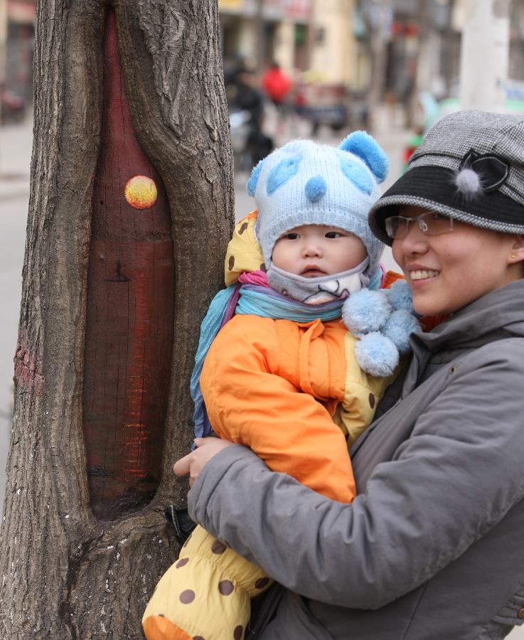 Citizens pose for photo with a tree hollow painting created by Wang Yue, a local college student, at Jiuzhong Street in Shijiazhuang, capital of north China's Hebei Province, March 1, 2013. (Xinhua/Ding Lixin)