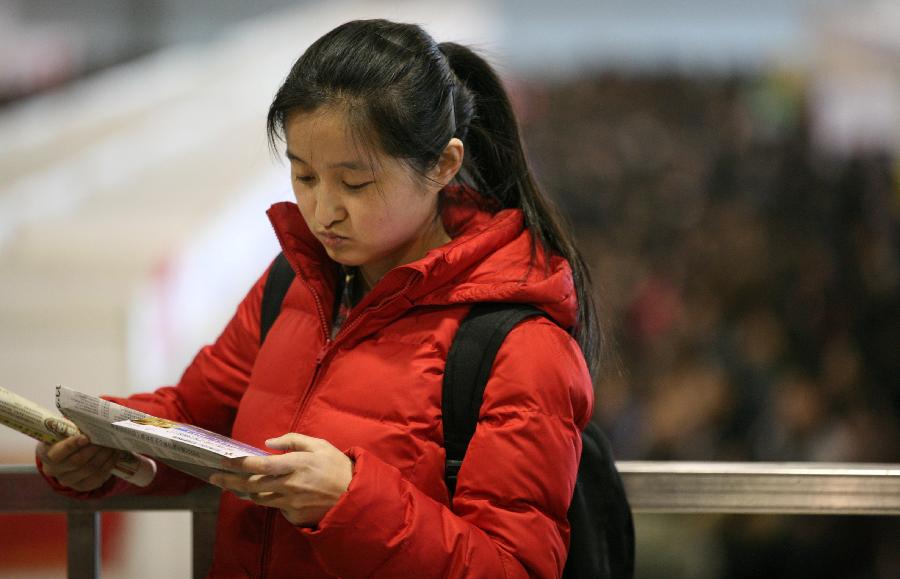 A job seeker reads employment information at a job fair in Nanjing, capital of east China's Jiangsu Province, March 2, 2013. More than 20,000 job opportunities were offered at the job fair. (Xinhua/Wang Xin)