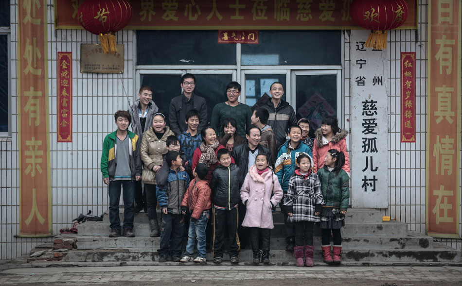 Lou Zongquan, Li Guifeng and some orphans they have adopted pose for photo in Yingkou of Liaoning on Feb. 26, 2013. Lou and his wife Li have adopted 34 orphans in 14 years. (Xinhua/Yao Jianfeng)