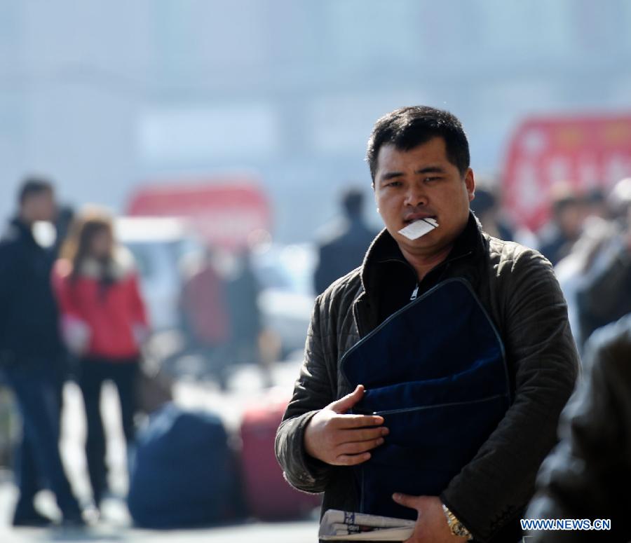 A passenger, holding a ticket in his mouth, walks on the square outside the railway station in Harbin, capital of northeast China's Heilongjiang Province, March 6, 2013. The 40-day Spring Festival travel rush, started on Jan. 26 this year, came to the last day on Wednesday. The Spring Festival, which falls on Feb. 10 this year, is traditionally the most important holiday of the Chinese people. It is a custom for families to reunite in the holiday, a factor that has led to massive seasonal travel rushes in recent years as more Chinese leave their hometowns to seek work elsewhere. (Xinhua/Wang Song) 