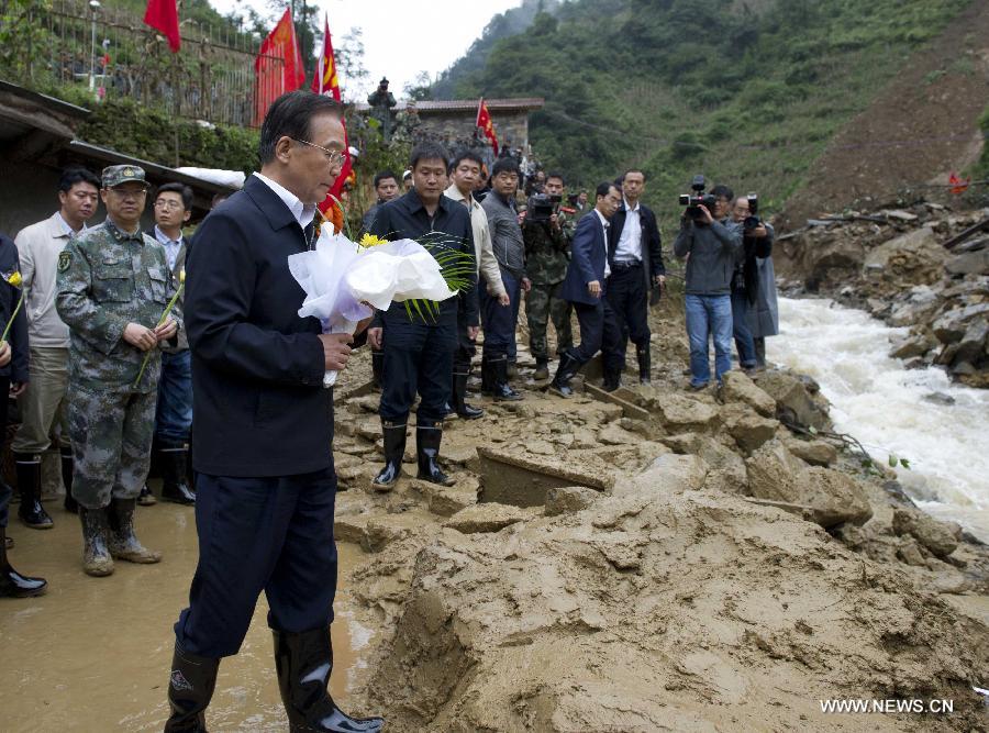 Chinese Premier Wen Jiabao (front) presents a bouquet for the victims of a landslide in the village of Zhenhe in Yiliang County, southwest China's Yunnan Province, Oct. 5, 2012. The landslide that occurred Thursday killed 18 primary school students and one villager. (Xinhua File Photo/Li Xueren)