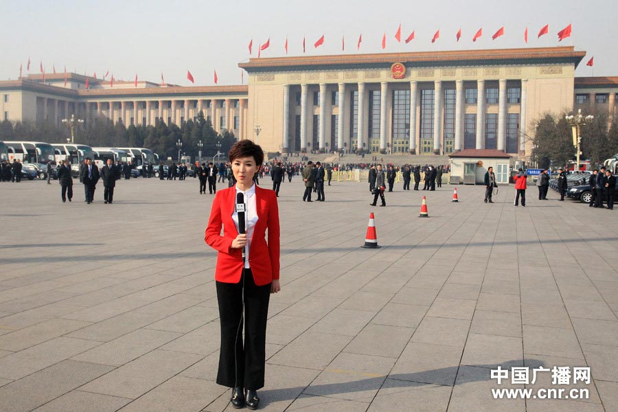A television host wearing red suit reports at Tiananmen Square. (Photo/www.cnr.cn)