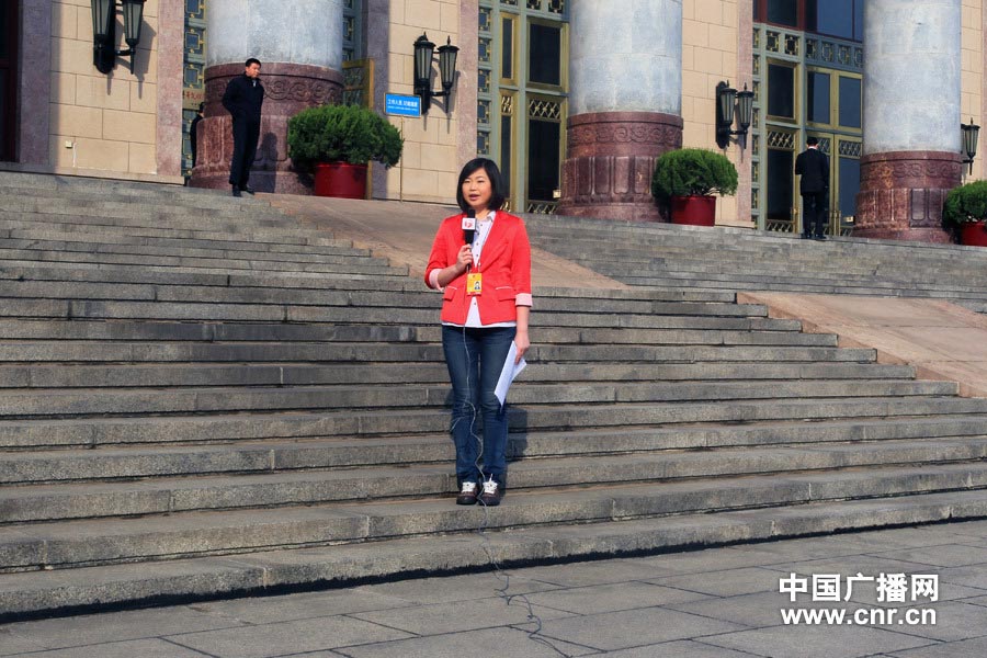 A television host wearing red suit reports at Tiananmen Square. (Photo/www.cnr.cn)