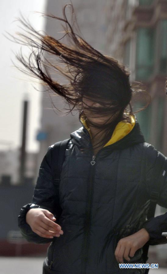 A woman walks in strong wind in Beijing, capital of China, March 9, 2013. A cold front brings strong wind as well as sand and dust to Beijing on March 9. (Xinhua/Li Wen)