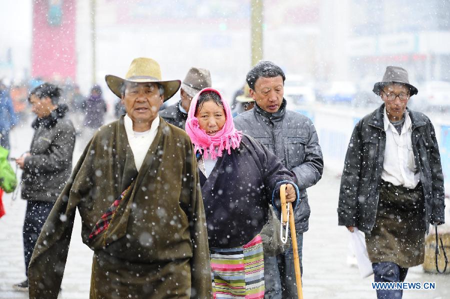 People walk in snow in Lhasa, capital of southwest China's Tibet Autonomous Region, March 11, 2013. (Xinhua/Liu Kun)