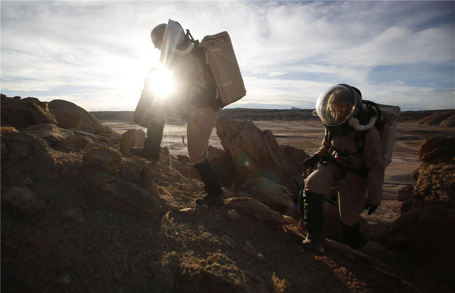 Melissa Battler (L), a geologist and commander of the Crew 125 EuroMoonMars B mission, and Csilla Orgel, a geologist, climb a rock formation to collect geologic samples for study at the Mars Desert Research Station (MDRS) in the Utah desert March 2, 2013.(Photo/Agencies)