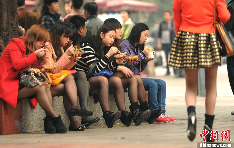 Chongqing girls wearing black silk stocking take a rest under tree; temperature in Chongqing is higher than 20 degrees Celsius on March 10, 2013. (Photo/CNS)