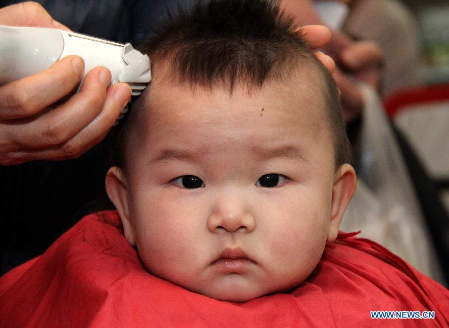 A baby has haircut at a barbershop in Zaozhuang City, east China's Shandong Province, March 13, 2013, on the occasion of the second day of the second lunar month, known in Chinese as Er Yue Er, "a time for the dragon to raise its head", as a Chinese saying goes. Barbershops across the country opened early to begin one of their busiest days of the year, as many Chinese hold the superstitious belief that getting a haircut at a time when the "dragon raises its head" means they will have a vigorous start to the new year. (Xinhua/Sun Zhongzhe)