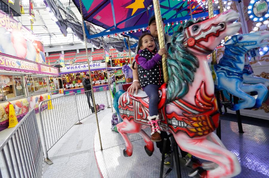 A girl enjoys carrousel at the Playdome carnival held at BC Place stadium in Vancouver, Canada. March 16, 2013. (Xinhua/Liang Sen) 