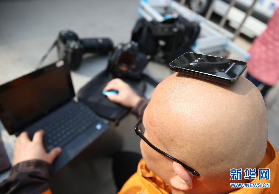 A journalist puts a network adaptor on his head to put his report online outside the Great Hall of the People. (Xinhua/ Wang Shen)