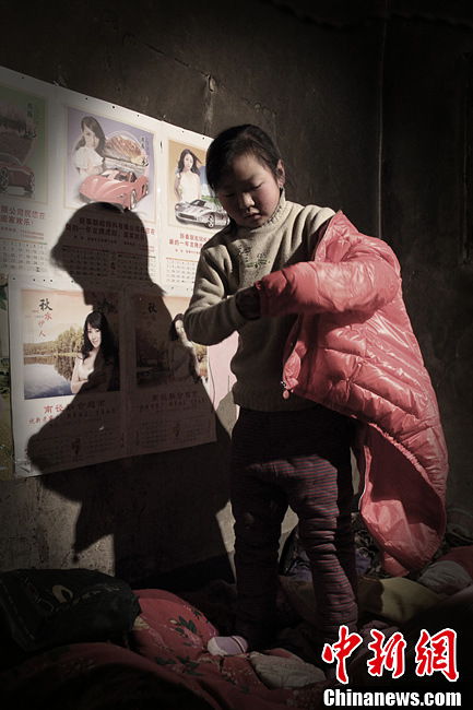 Song Juan puts on the new jacket, a gift from the photographer. She is very happy and tells in shyness that the last jacket was bought when her father was alive. (Chinanews.com/ Zhou Panpan)