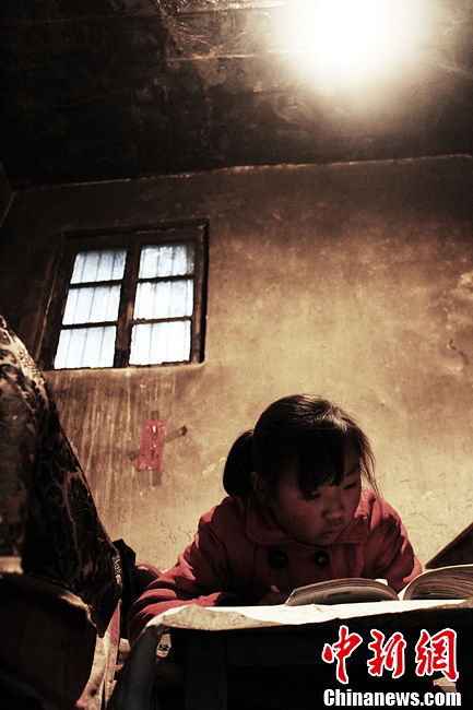 Song does her homework in the dim of light. (Chinanews.com / Zhou Panpan)