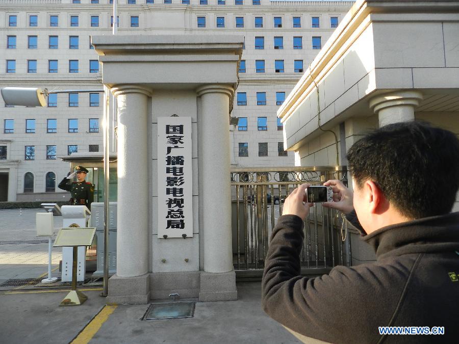 A man takes photos of the old plate of the State Administration of Radio, Film and Television before the ceremony to hang the new one in Beijing, capital of China, March 22, 2013. China's National People's Congress, the country's top legislature, has adopted a cabinet reshuffle plan in which two media regulators, the General Administration of Press and Publication and the State Administration of Radio, Film and Television, were merged into a single entity to oversee the country's press, publication, radio, film and television sectors. (Xinhua/Wang Zhen)
