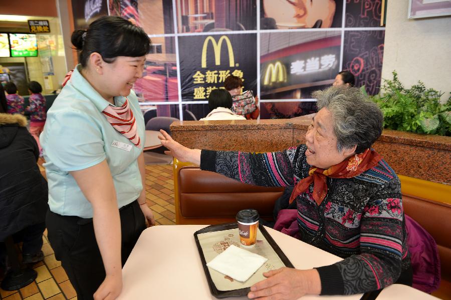 A staffer brings a cup of tea to 75-year-old Li Shufen, an old customer who lives in the neighborhood, at the McDonald's restaurant at Chang'an Market in Beijing, capital of China, March 24, 2013. Opened in 1993 as the second outlet of the American fast-food giant in Beijing, the Chang'an Market McDonald's made indelible impressions on locals. Due to reconstruction and adjustment of the market, the outlet discontinued its business Sunday. (Xinhua/Li Xin)