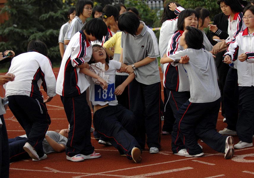 Some girls of the Jiaxing No.1 High School are too exhausted to walk after the 800-meter race on Oct. 16, 2008. Though their spirit of determination was greatly applauded by the audience, it still required both the school and the parents to rethink the students' physical condition. (Zhejiang Daily/Chu Yongzhi)