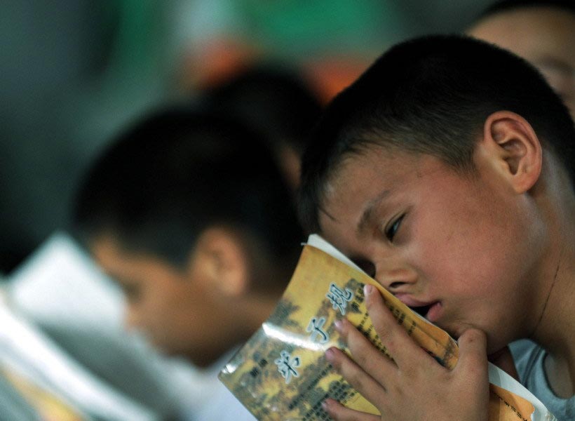 On Aug. 16, 2010, a student is seen dozing off during a summer class with the "Standards for Students" booklet clutched in his hands. Children's lives are often overtaken by various training classes during their holidays. (Zhejiang Daily/Chu Yongzhi)