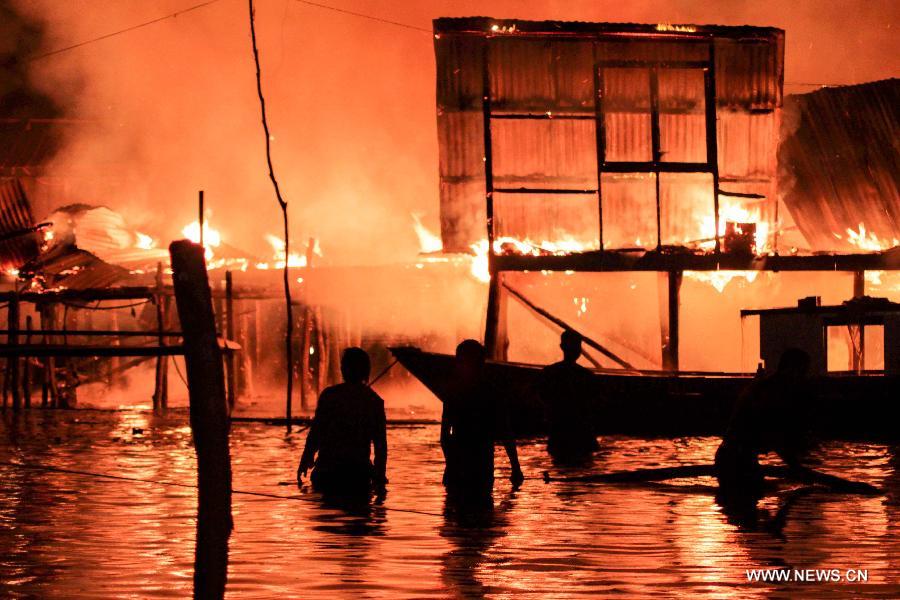 Fire fighters try to put out a fire in Kota Kinabalu, Malaysia, March 27, 2013. A fire engulfed over 400 wooden houses on the sea on Wednesday, leaving more than 3,000 people homeless and dozens injured. (Xinhua) 