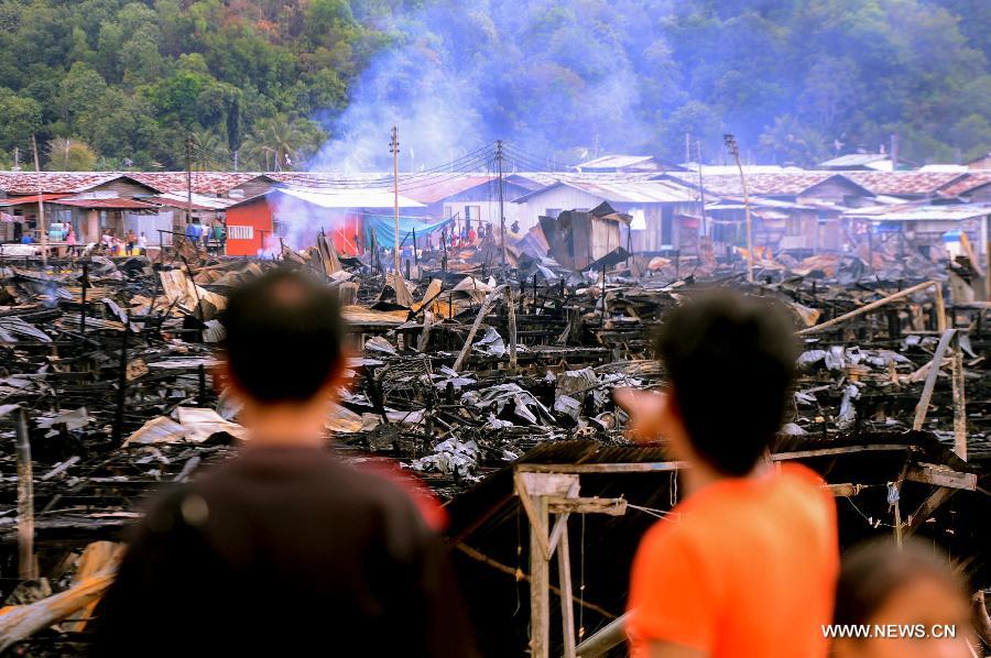 People look at the remains of the wooden houses after a fire in Kota Kinabalu, Malaysia, March 28, 2013. A fire engulfed over 400 wooden houses on the sea on Wednesday, leaving more than 3,000 people homeless and dozens injured. (Xinhua) 
