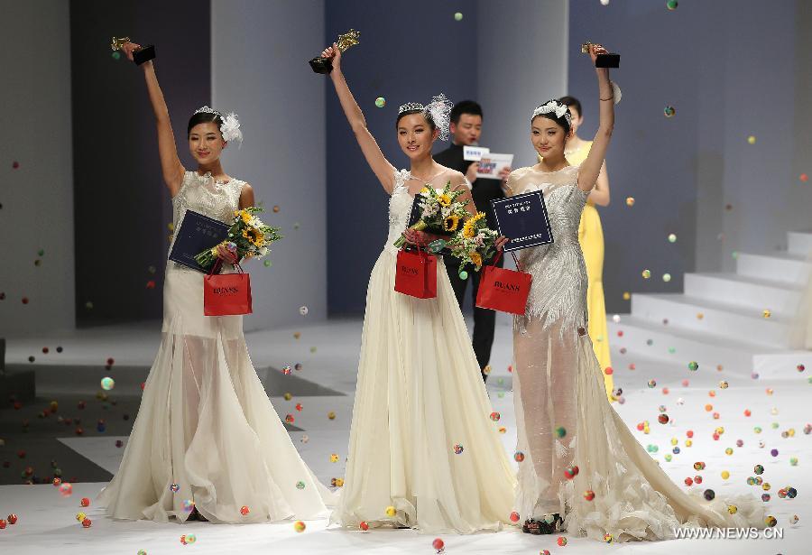 Champion Zhang Lingyue (C), runner-up Zhao Siyu (L) and second runner-up Lei Shuhan greet the audience during the 8th China Super Model Final Contest in Beijing, capital of China, March 30, 2013. (Xinhua/Wan Xiang)