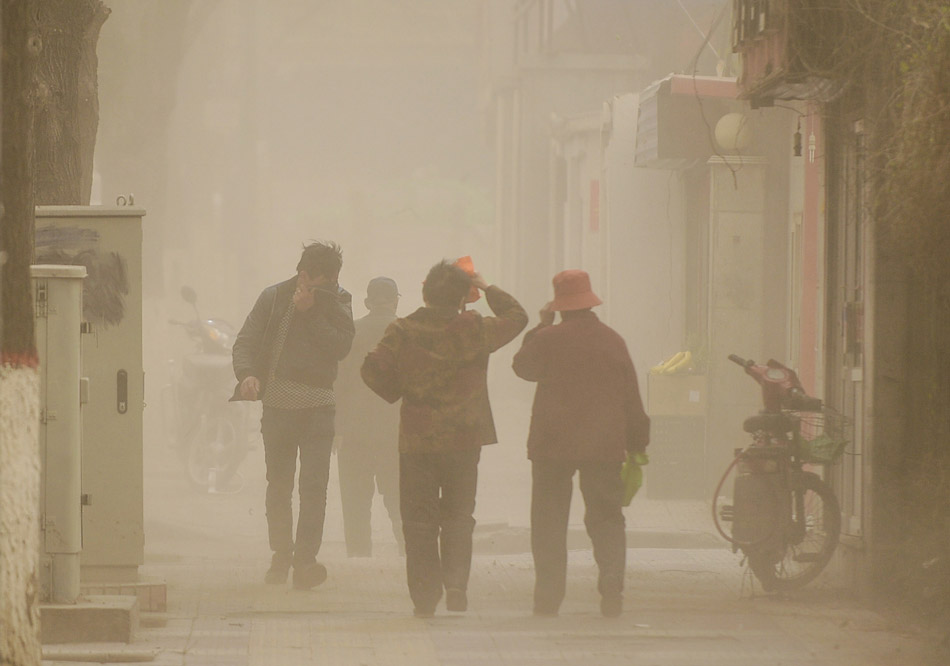 Some people brave blowing dust and walk in the streets of Xining, Qinghai province. (Xinhua/Wu Gang)