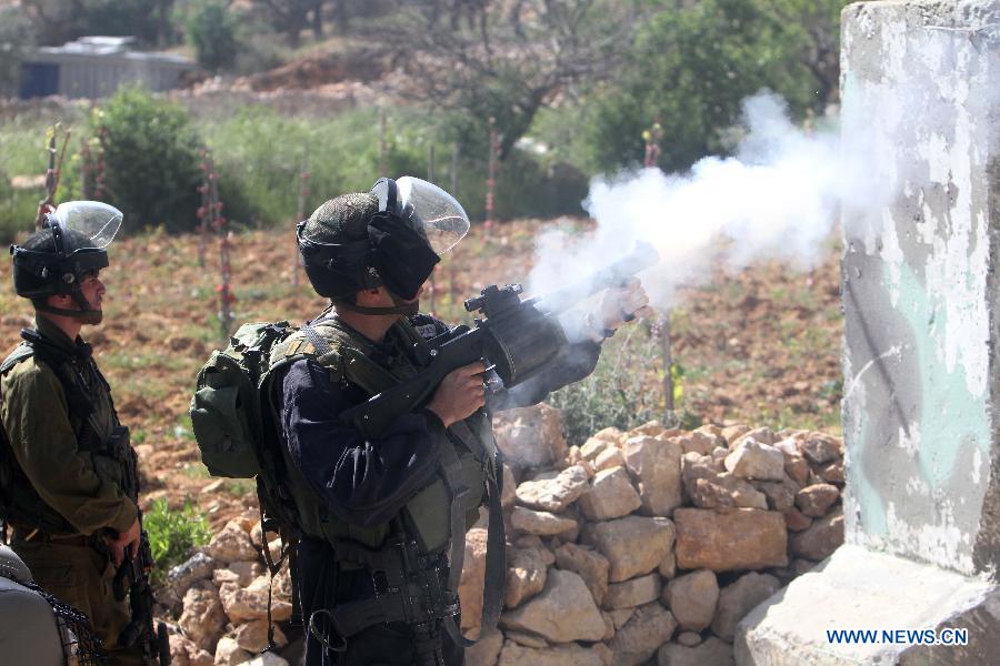 An Israeli soldier shoots tear gas toward Palestinian protesters during clashes in the West Bank village of Al-Khader near Bethlehem on March 29, 2013. (Xinhua/Luay Sababa) 