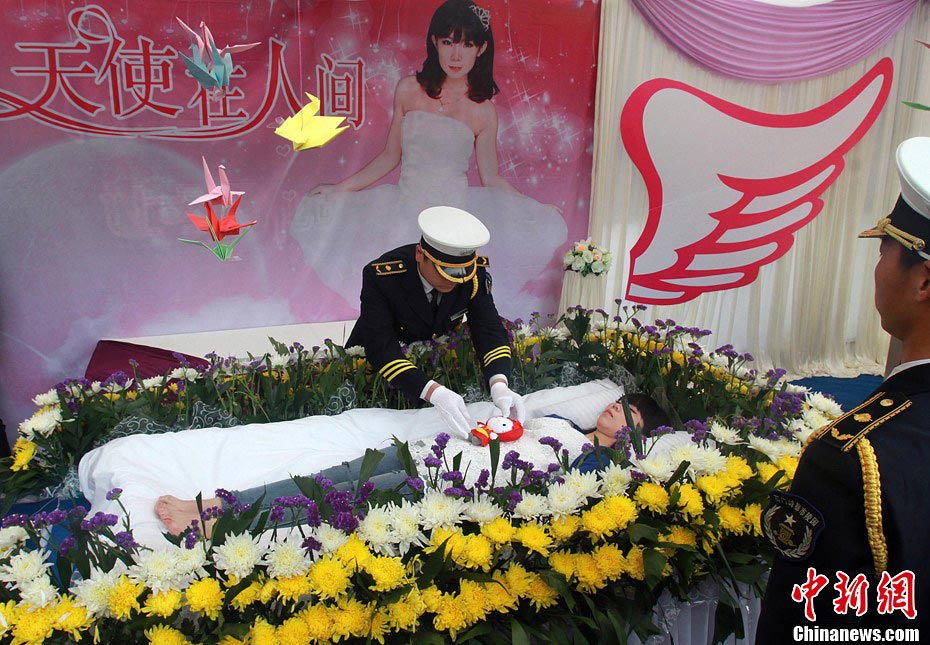 A pallbearer adjusts the clothes for Zeng Jia, a college student who staged her own fake funeral in Wuhan, Central China's Hubei province, March 30, 2013. The faux funeral, aimed at making people think about living through and finding your true self, was the idea of Zeng after her grandfather passed away. "I feel so good living after coming out of the coffin", said the student who studied funerals. (Photo/CNS)