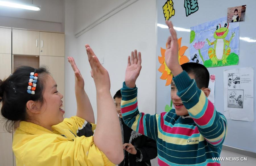 Teacher Lin Dan (L) interacts with autistic children at Xingyu School in Fuzhou, capital of southeast China's Fujian Province, March 28, 2013. The Xingyu School, offically opened to public in February this year, is a nine-year compulsory education school founded specifically for autistic children. It combines the characteristics of normal primary schools and autism rehabilitation centers, and provides both linguistic and behavior trainings to autistic children for their better intergration into the society in the future. (Xinhua/Lin Shanchuan)