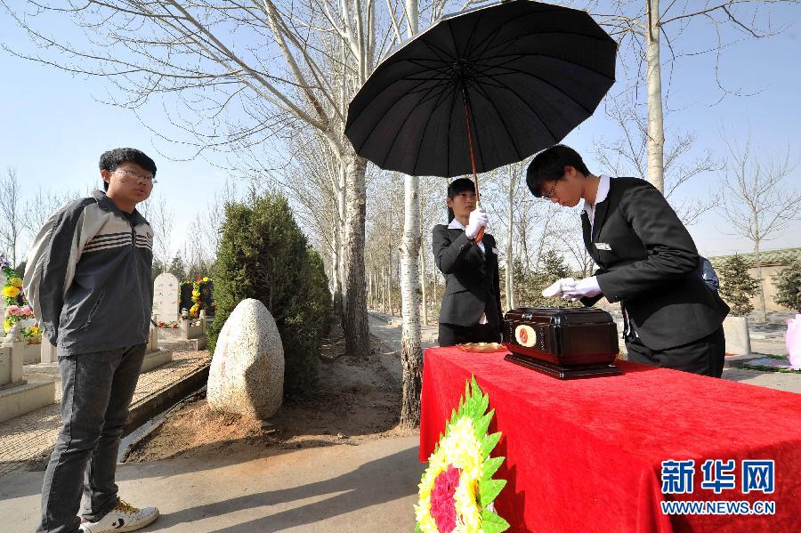 Funeral director Wang Na (R) cleans an urn at a funeral in a cemetery in Yinchuan city, capital of Northwest China's Ningxia Hui autonomous region, on April 2, 2013. [Photo/Xinhua] 